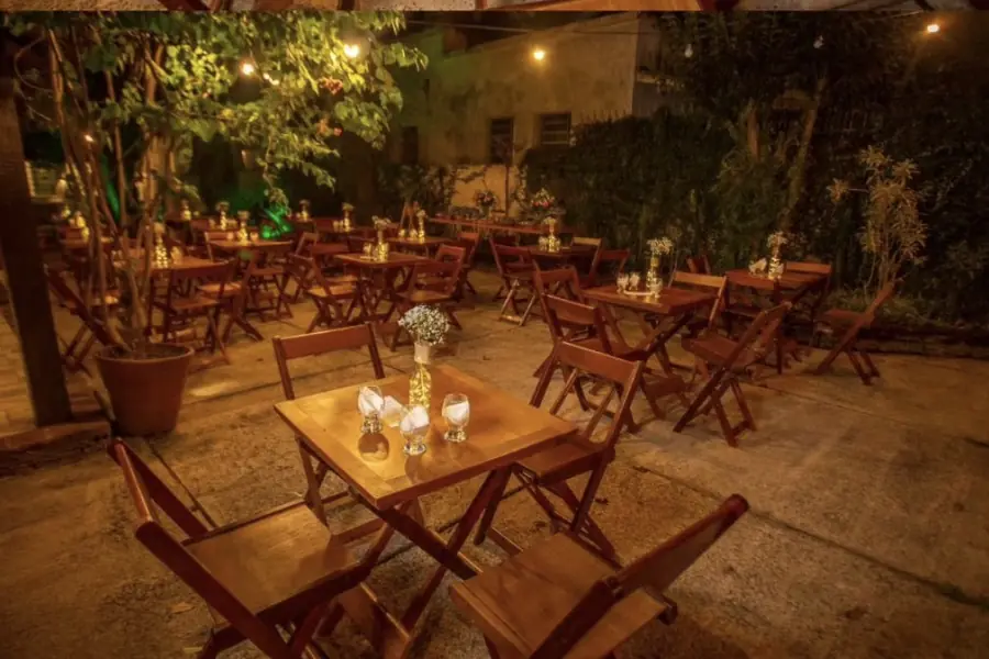 Área externa iluminada com mesas montadas para evento em Uruguaiana