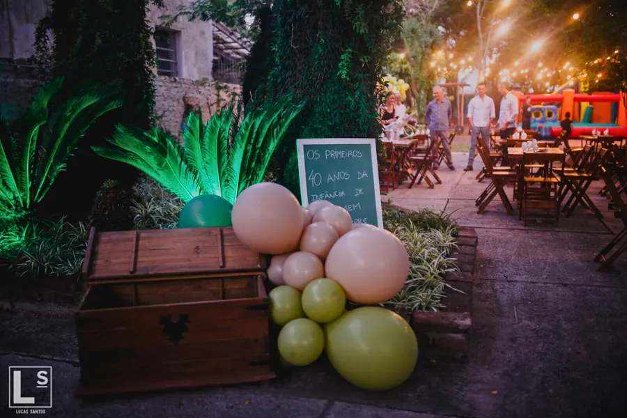 Decoração com balões e baú de madeira em festa ao ar livre à noite em Uruguaiana