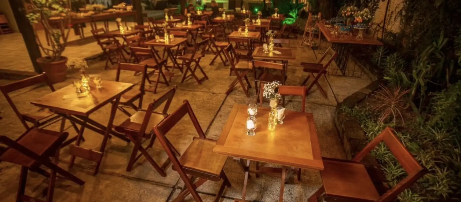 Mesas com velas acesas em evento noturno na área externa do Lamora’s Eventos em Uruguaiana